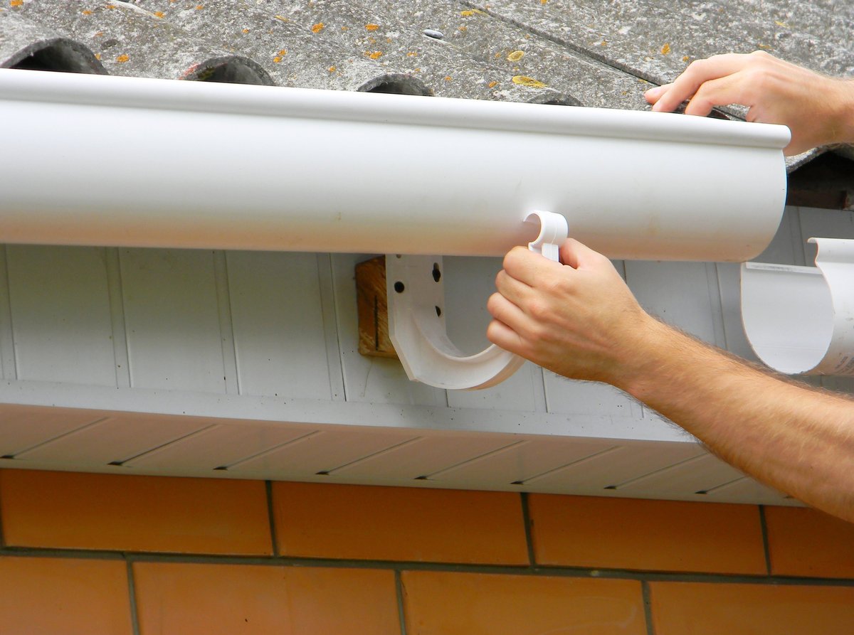 Contractor installing a plastic roof gutter and drainage
