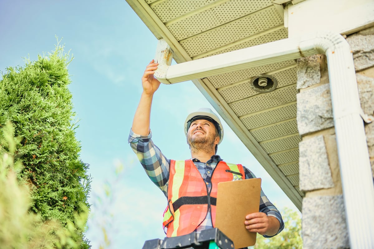 Professional inspecting the gutter system on a residential home