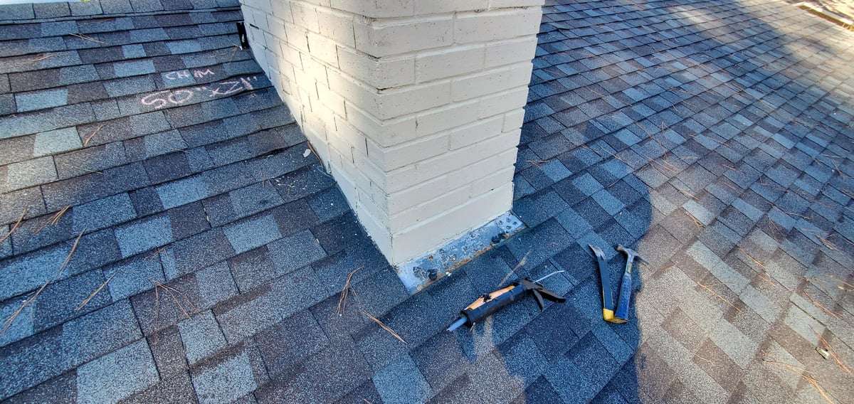 Technical inspection view of a residential brick chimney with metal cap and counter-flashing