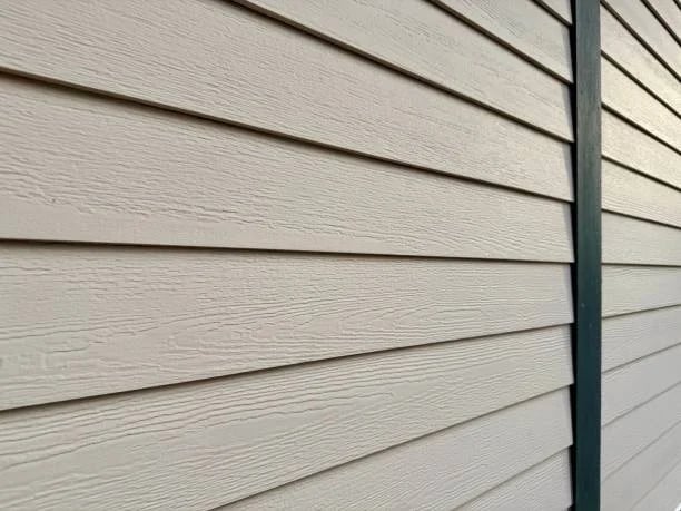 Close-up of horizontal fiber cement siding boards on a building exterior with a dark vertical trim piece